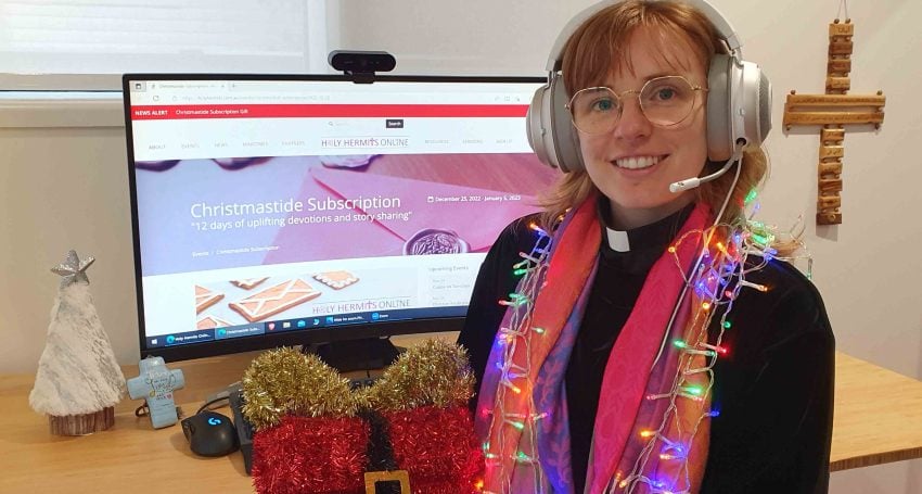 Woman priest wearing tinsel and lights in front of a computer