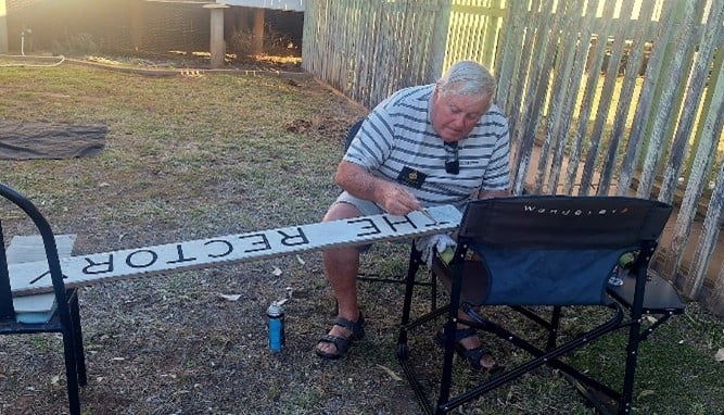 Man painting a rectory sign in the outback 