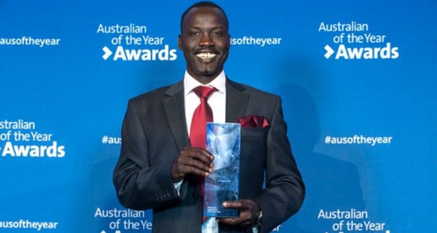 Man in a suit holding a Perspex Australia Day award