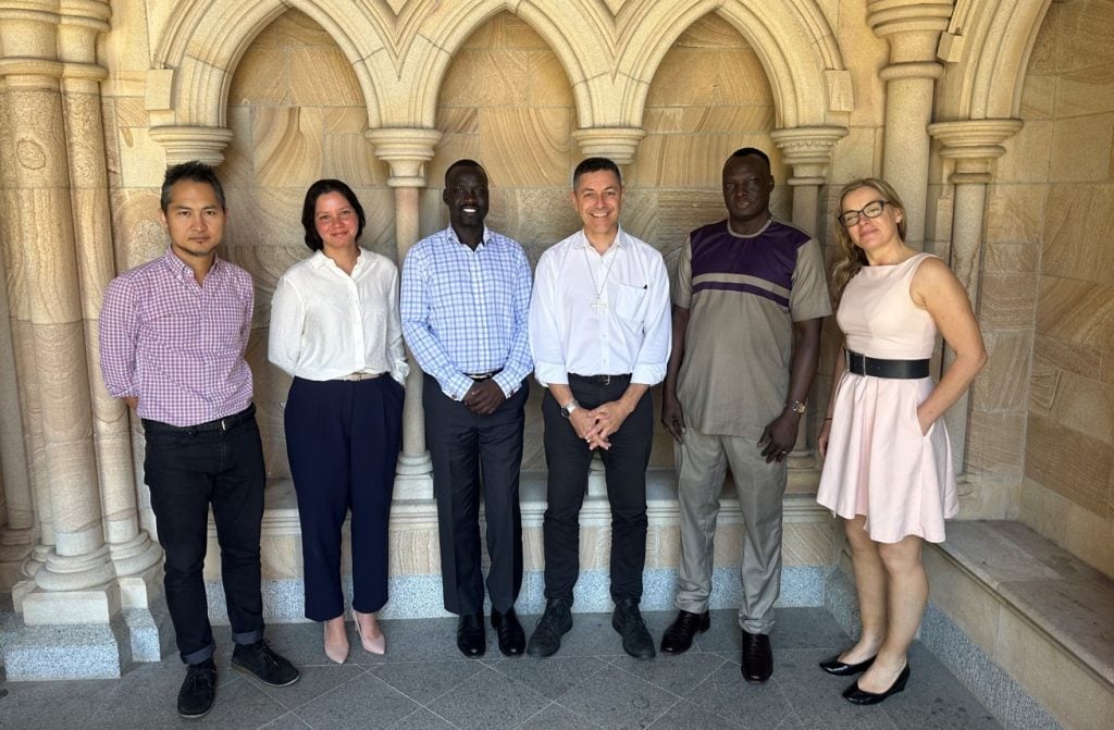 Six diverse people outside a Cathedral smiling, including an Archbishop and a Bishop