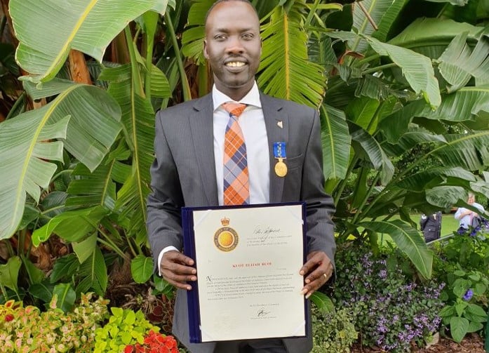 Man in suit holding a certificate in a garden 