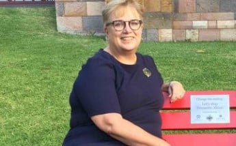 Woman in navy dress sitting on red bench