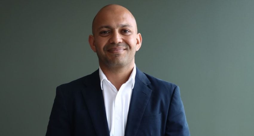 Man in white shirt and dark jacket looking at the camera smiling