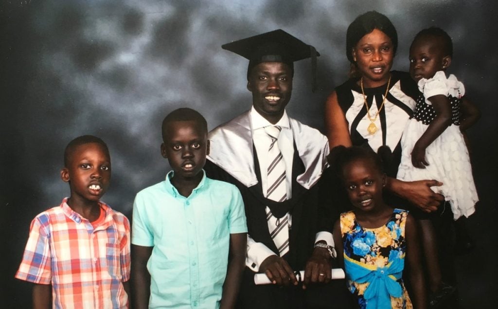 A mother and father and four kids at the father's graduation ceremony