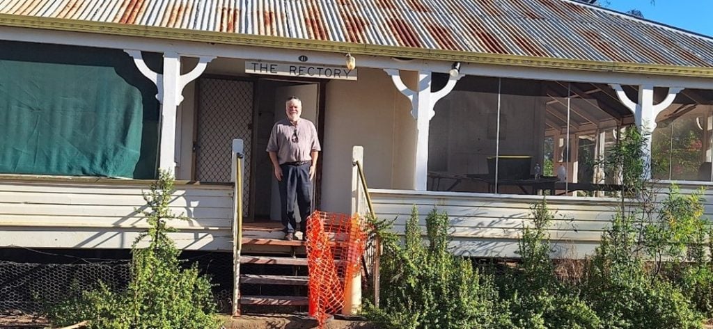 Outback priest standing on an outback rectory verandah 