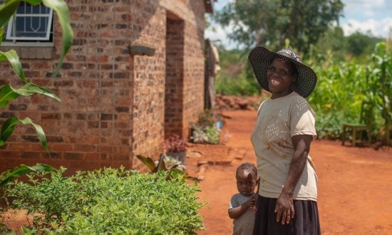 Woman and her young son in front of a house in Zimbabwe