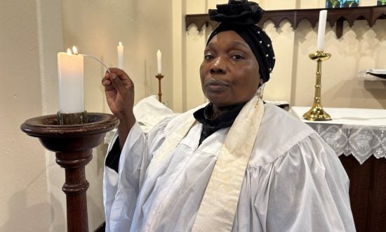 Sudanese priest lighting a candle in prayer