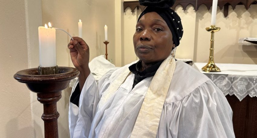 Sudanese priest lighting a candle in prayer