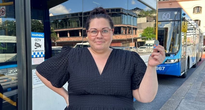 Woman at a bus stop holding up a 50-cent piece