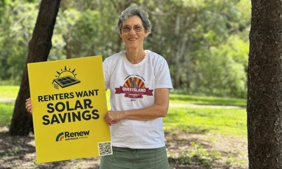 Woman wearing a white t-shirt in a park holding a sign