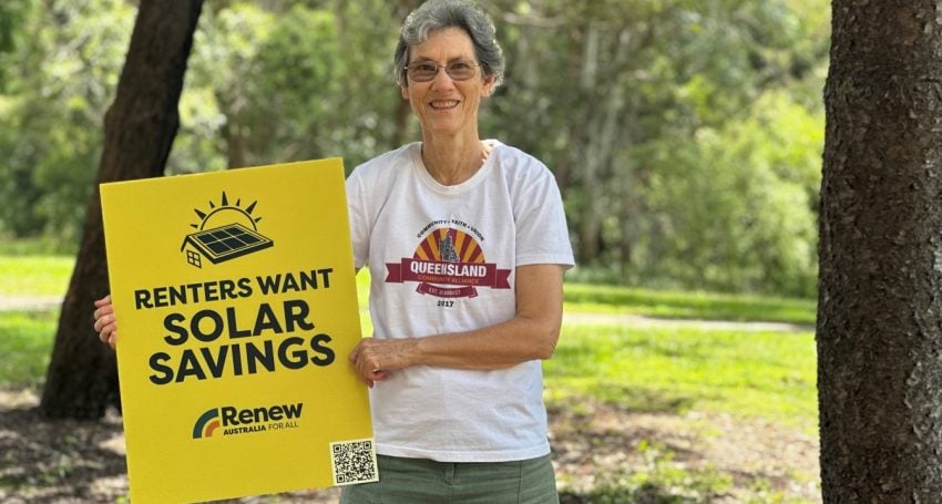 Woman wearing a white t-shirt in a park holding a sign