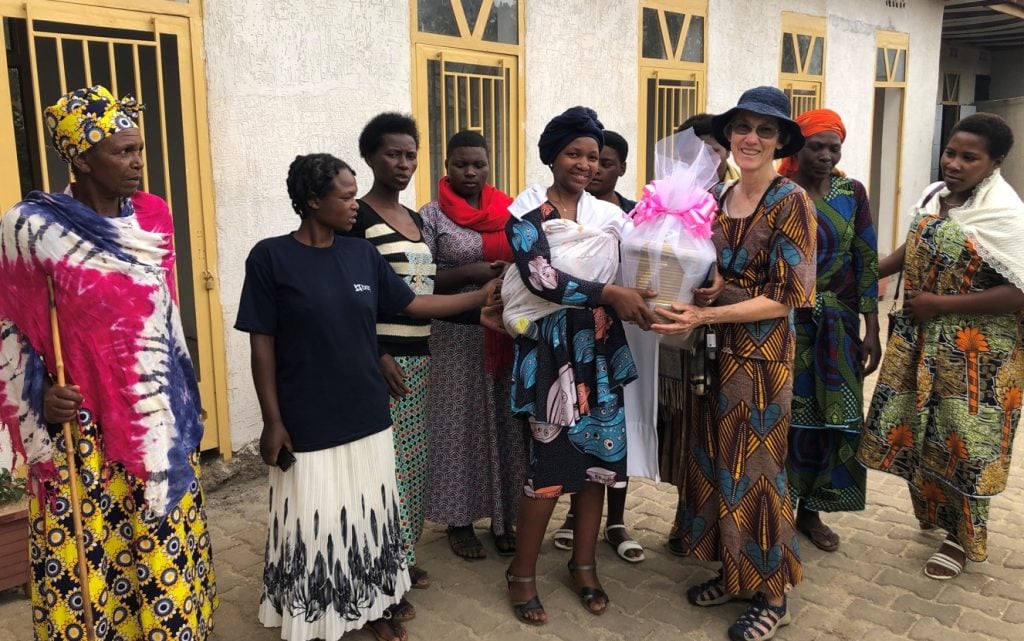 Woman being welcomed in an African village as she visits: she is being presented with flowers 