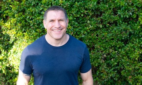 Man in dark blue t-shirt in front of a green bush