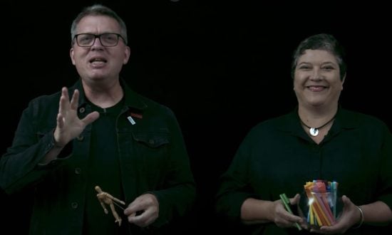 Man and woman wearing black against a black screen holding art and stationery items