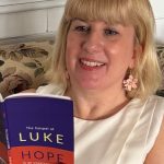 Woman with blonde hair holding a gospel of Luke book