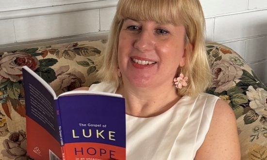 Woman with blonde hair holding a gospel of Luke book