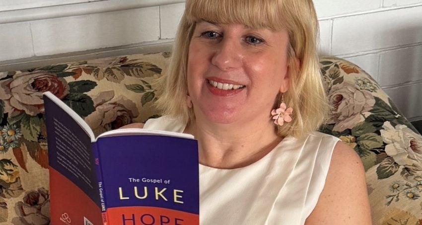 Woman with blonde hair holding a gospel of Luke book