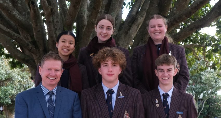 A group of Toowoomba Anglican School students and staff involved with the school's newly created Amnesty International Group, standing in front of a large tree