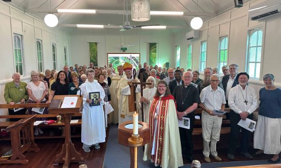 A large group of people stand in a church hall posing for a photograph