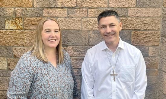 A woman and an Archbishop standing in front of a cathedral's limestone bricks