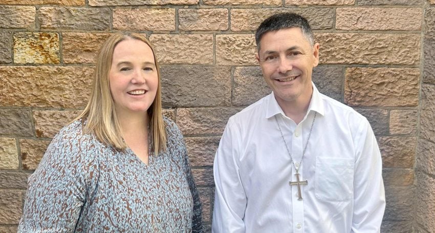A woman and an Archbishop standing in front of a cathedral's limestone bricks