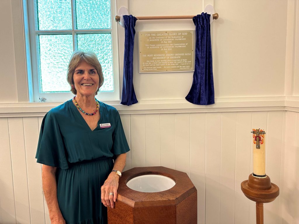 A woman poses for a photograph in a church hall