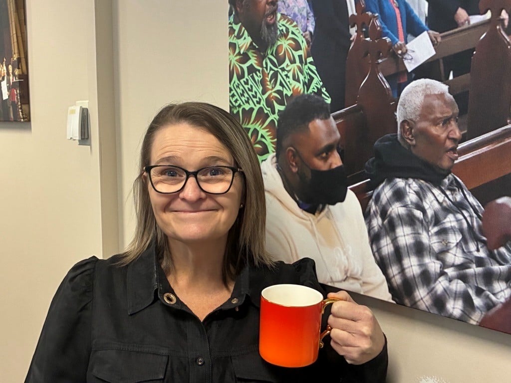 A woman poses for a photograph holding a coffee cup