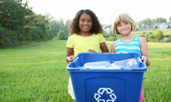 Tow girls holding a blue bucket of plastic bottles