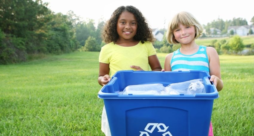 Tow girls holding a blue bucket of plastic bottles