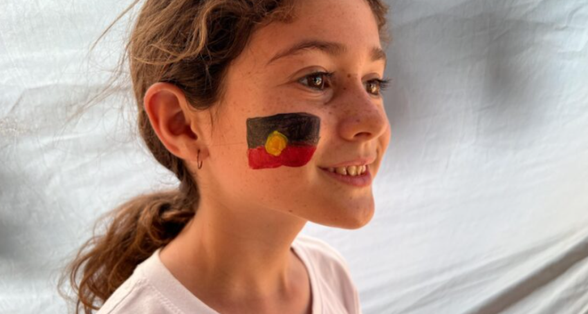 A young girl with an Aboriginal flag painted on her cheek