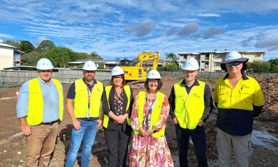 A group of Woollam and Anglicare Southern Queensland staff standing at a construction site.