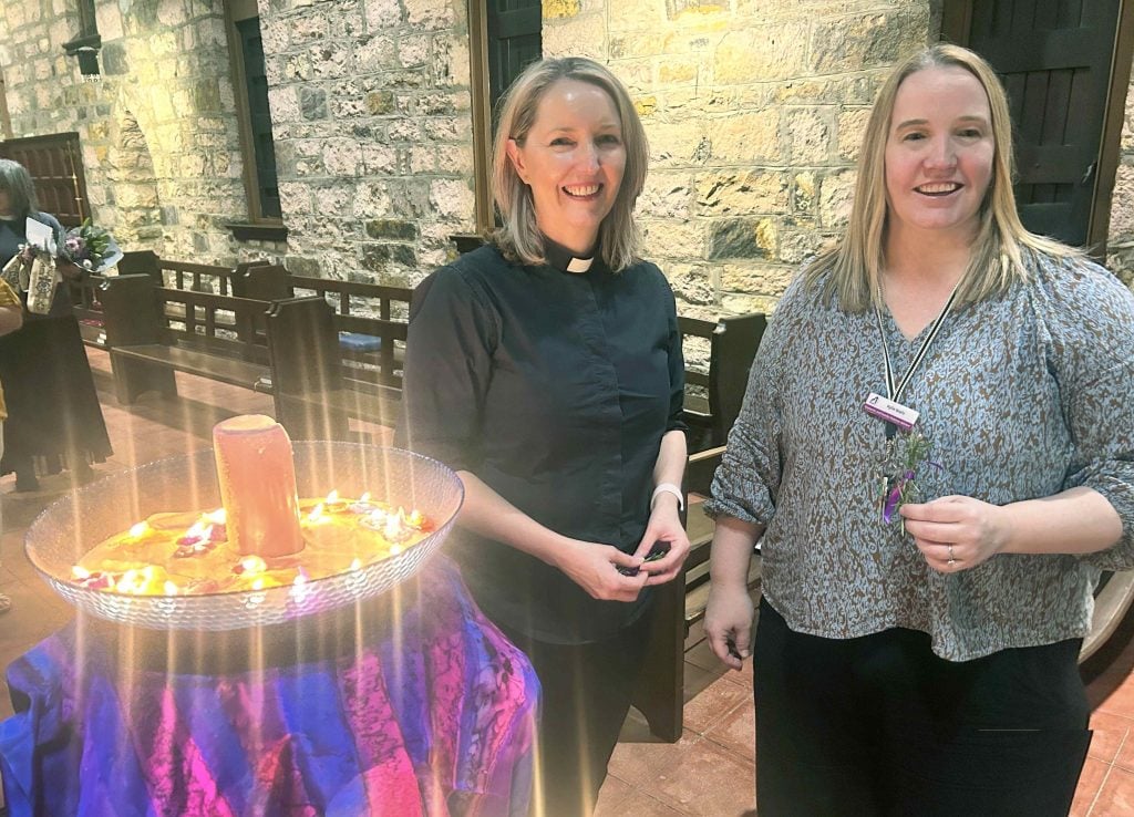 A priest and a woman in a cathedral near a bowl of candles