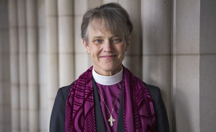 Woman bishop wearing a collar and purple shawl
