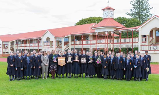 A large group of students and staff stand outside posing for a photograph