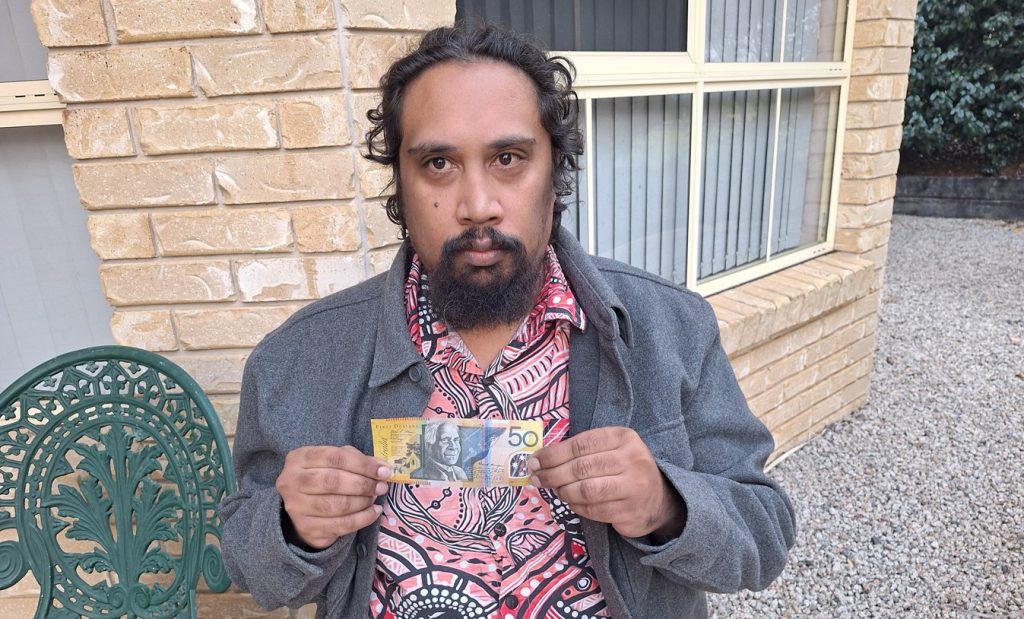 Man holding up a $50 note