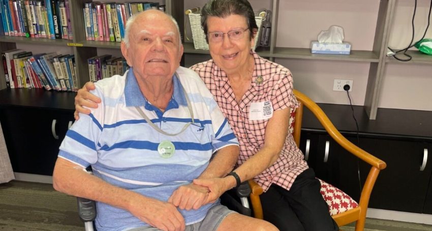 Two people pose for a photograph in a residential aged care facility