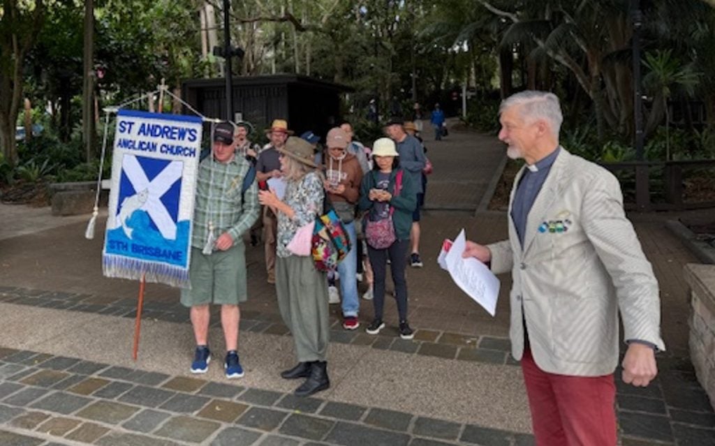 Church folk walking in a procession led by a person carrying a church banner
