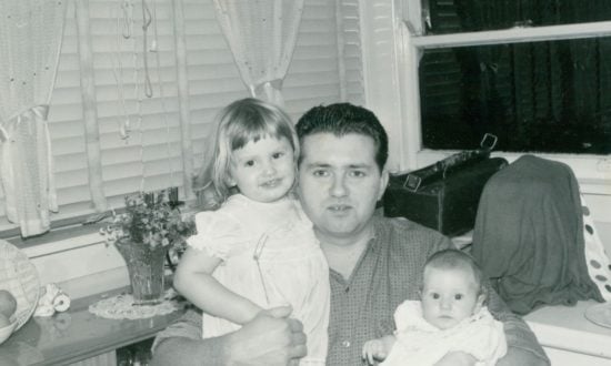 Man holding his two daughters in the 1960s at home