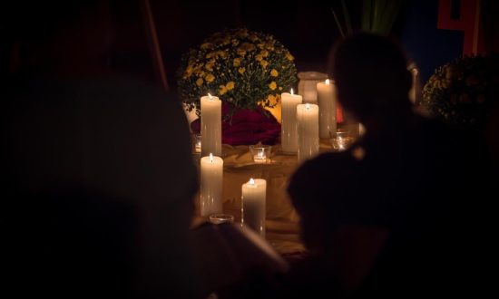 People congregate around candles in a dimly lit space