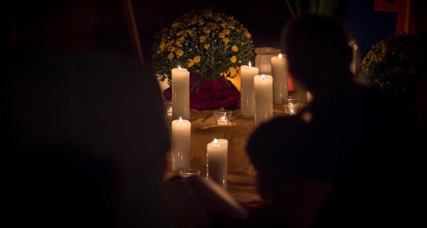 People congregate around candles in a dimly lit space