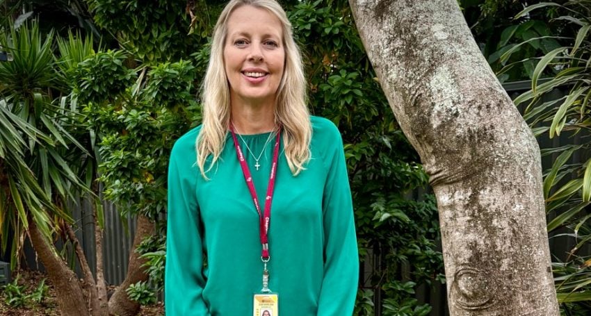 Woman in green long-sleeved top with lanyard around her neck