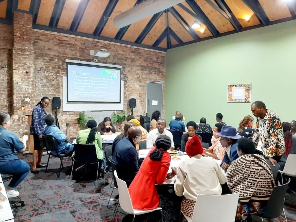 Large group of African people in a room sitting around tables during a workshop