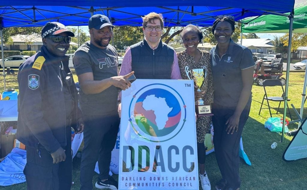 Five people around a Darling Downs African Communities Council sign, with one holding a trophy