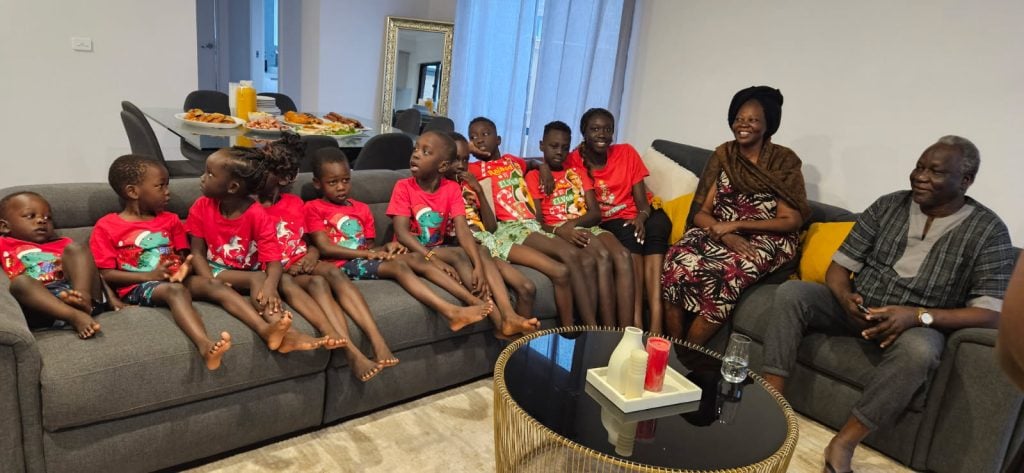 Nine South Sudanese kids and three adults sitting on a couch