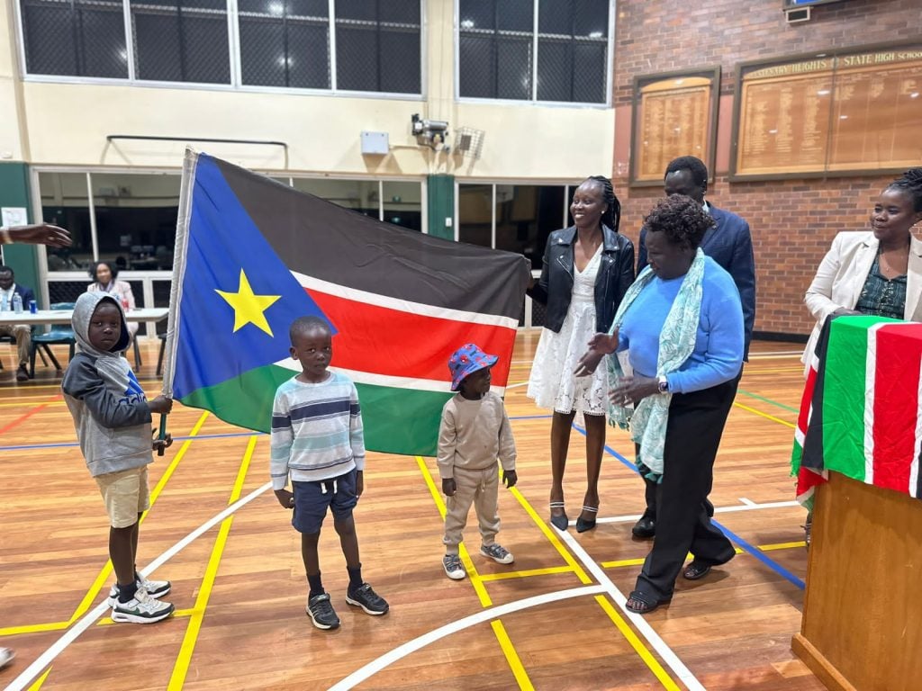 South Sudanese people holding a South Sudan flag in a gymnasium