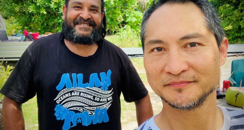 Two men pose for a selfie photograph outside