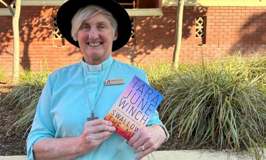 Woman priest in blue shirt wearing an Akubra hat and holding a book