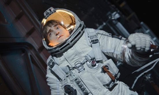 A man in a space suit holds on to some spaceship machinery