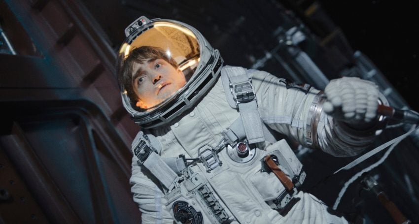A man in a space suit holds on to some spaceship machinery