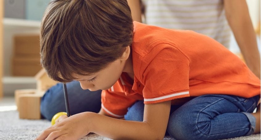 A child is on the floor drawing